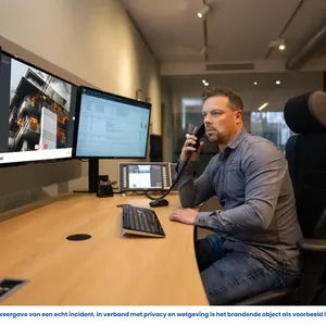 Man belt terwijl hij via WeSeeDo op zijn scherm een brandend gebouw ziet, symbool voor snelle visuele communicatie bij incidenten.