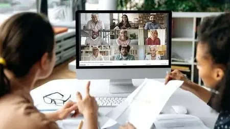 Twee medewerkers voeren via WeSeeDo een videogesprek met zes andere deelnemers.